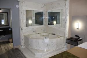 a bathroom with a large white marble bath tub at Milan inn & Suites in Milan +9 photos