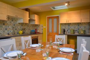 a kitchen with a wooden table with plates and glasses on it at Dunmore Coastal Retreat in Dunoon