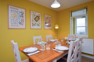 a dining room with a wooden table and white chairs at Dunmore Coastal Retreat in Dunoon +18 photos