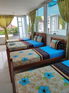 three beds in a room with windows at Hospedaje casa Lucía in Leticia