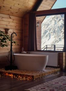 a bath tub in a room with a large window at Kera Cottages Kazbegi in Kazbegi