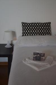 a bed with a black and white pillow and a blanket at Tenuta Roletto Cascina Guie in Cuceglio