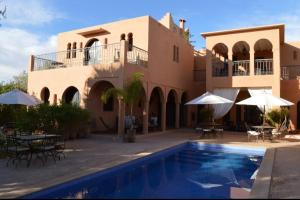 a villa with a swimming pool and tables and umbrellas at Riad Jardin des Orangers in Taroudant
