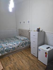 a small bedroom with a bed and a dresser at Quarto Ametista in Aracaju