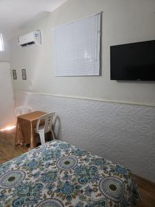 a bedroom with a bed and a flat screen tv at Quarto Ametista in Aracaju