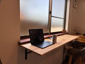 a laptop computer sitting on a desk in front of a window at 細島 Base Clutch in Hyuga