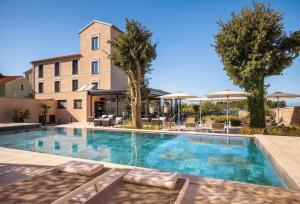a swimming pool with chairs and umbrellas in front of a building at DUNATOVI DVORI Heritage Hotel in Preko