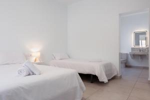 a white bedroom with two beds and a mirror at Hostal España in Arrecife