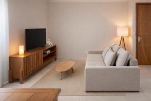 a living room with a couch and a tv at Apê 301 - Central, Garagem, Ar-Cond - 2 Quartos in Governador Valadares