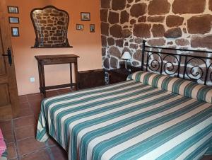a bedroom with a bed and a stone wall at CASA RURAL MATÉ in Susilla