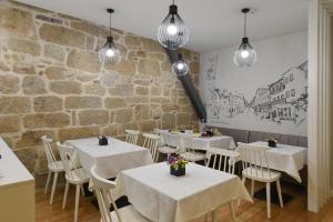 a restaurant with white tables and chairs and a stone wall at VILA DE PONTE GUEST HOUSE in Ponte de Lima +33 photos