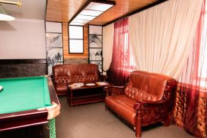 a pool room with leather chairs and a pool table at GALIRAD Hotel in Ustʼ-Kamenogorsk