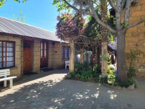 a brick building with a tree and a bench at Sandstone Escape Guesthouse in Ladybrand
