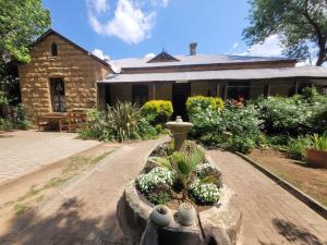 a house with a garden with flowers and a fountain at Sandstone Escape Guesthouse in Ladybrand +13 photos