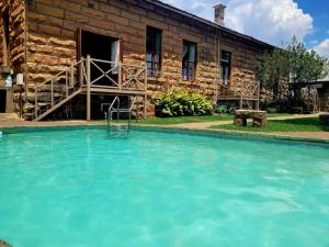 a swimming pool in front of a stone house at Sandstone Escape Guesthouse in Ladybrand