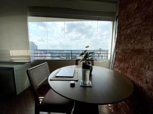 a table with a laptop on it in front of a window at Central Studio in the metro Butantã in São Paulo