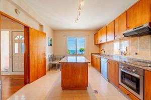 eine große Küche mit Holzschränken und einem großen Fenster in der Unterkunft Oceanview room in Ponta Delgada