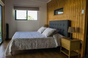 a bedroom with a bed with a blue headboard and a table at Te Manu Lodge in Hanga Roa