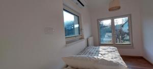 a white room with a bed and two windows at Apartments AlpRoza in Zgornje Gorje