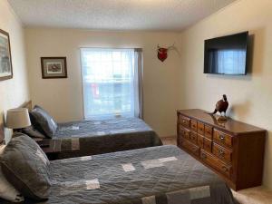 a bedroom with two beds and a dresser and a television at High Plains Hideout 3 bedrooms 2 Baths in WaKeeney