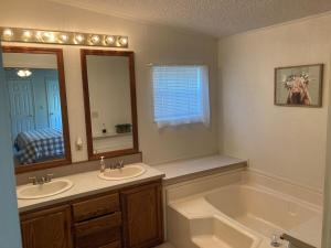 a bathroom with two sinks and a tub and a mirror at High Plains Hideout 3 bedrooms 2 Baths in WaKeeney +4 photos