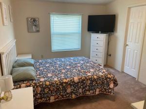 a bedroom with a bed and a dresser with a television at High Plains Hideout 3 bedrooms 2 Baths in WaKeeney