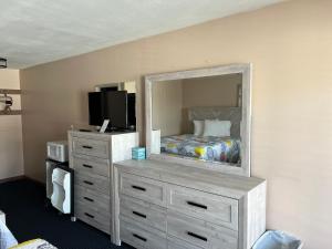 a bedroom with a dresser with a mirror and a bed at Regal Inn Hampton Beach in Hampton