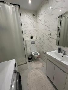 a white bathroom with a toilet and a sink at Аблайхана 1 г in Kokshetau