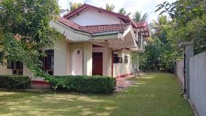 a white house with a fence and a yard at wkholiday home in Weligama