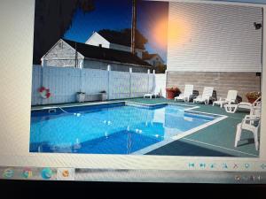 a large swimming pool with chairs and a fence at Regal Inn Hampton Beach in Hampton