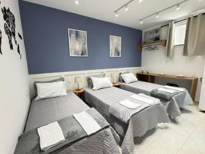 three beds in a room with blue walls at Pousada Minas Gerais in Araxá