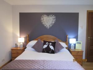 a bedroom with a large bed with two lamps on it at Broomlea in Inverness