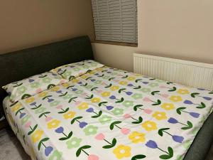 a bed with a comforter with flowers on it at Comfy En-suite room in Gloucester
