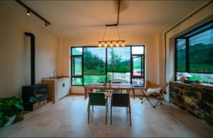 a dining room with a table and chairs and windows at 伴山一墅 in Chaoyang