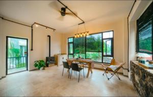 a dining room with a table and chairs and windows at 伴山一墅 in Chaoyang