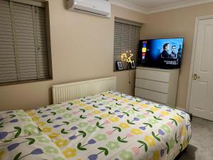 a bedroom with a bed and a flat screen tv at Comfy En-suite room in Gloucester +6 photos