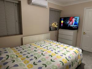 a bedroom with a bed and a flat screen tv at Comfy En-suite room in Gloucester