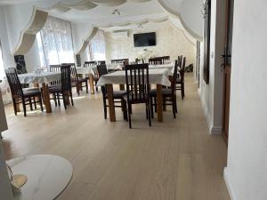 a dining room with tables and chairs and a tv at Pensiunea Hanzu Darius in Gura Râului