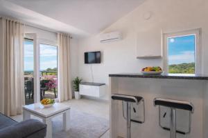 a living room with a kitchen with a counter and a table at LUNA Residence in Novalja