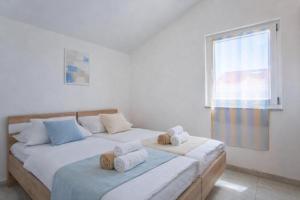 two beds in a white room with towels on them at LUNA Residence in Novalja