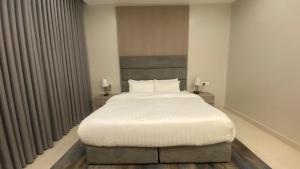 a bedroom with a large bed with white sheets at luxury royal apartments in Taif