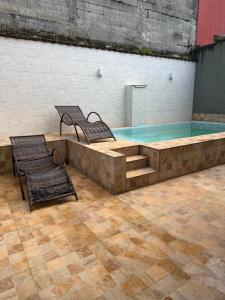 a swimming pool with two chairs and a bench at Casa em Condomínio in Bertioga +11 photos