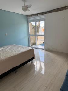 a bedroom with a bed and a large window at Casa em Condomínio in Bertioga
