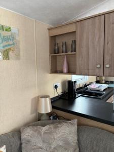 a living room with a couch and a kitchen at Sleeps 8 guests lovely 3 Bedroom Golden Gate Towyn in Llanddulas