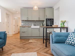 a kitchen with white cabinets and a blue couch at Shamrock in Exeter