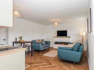 a living room with two blue chairs and a tv at Shamrock in Exeter