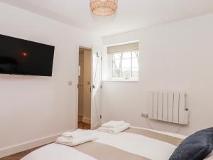 a white room with a bed and a tv on the wall at Shamrock in Exeter