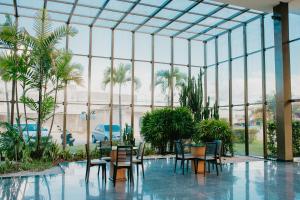 a conservatory with tables and chairs and palm trees at Cambuci Hotel in Camaçari