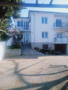 a large white house with a brick courtyard at Apartman Petra in Senj