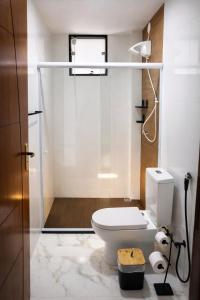 a bathroom with a white toilet and a shower at oceanic suítes in Araruama